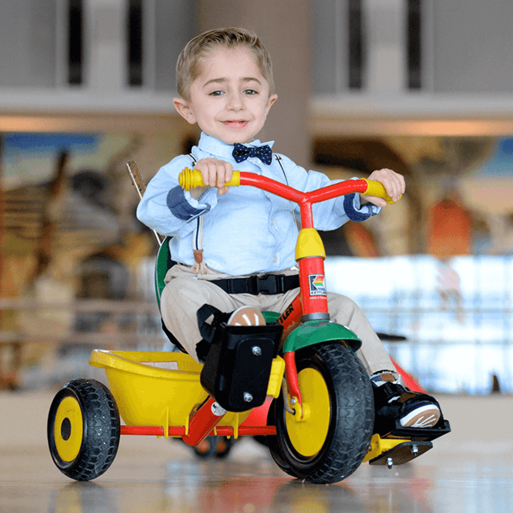shriners patient Kaleb rides toy bike in hospital