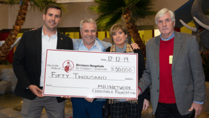 Four representatives from MRI Network display oversized check donation