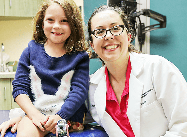 Girl Shriners patient with prosthetic leg smiles alongside female doctor