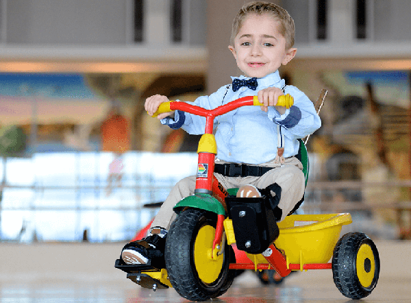 shriners patient Kaleb rides toy bike in hospital