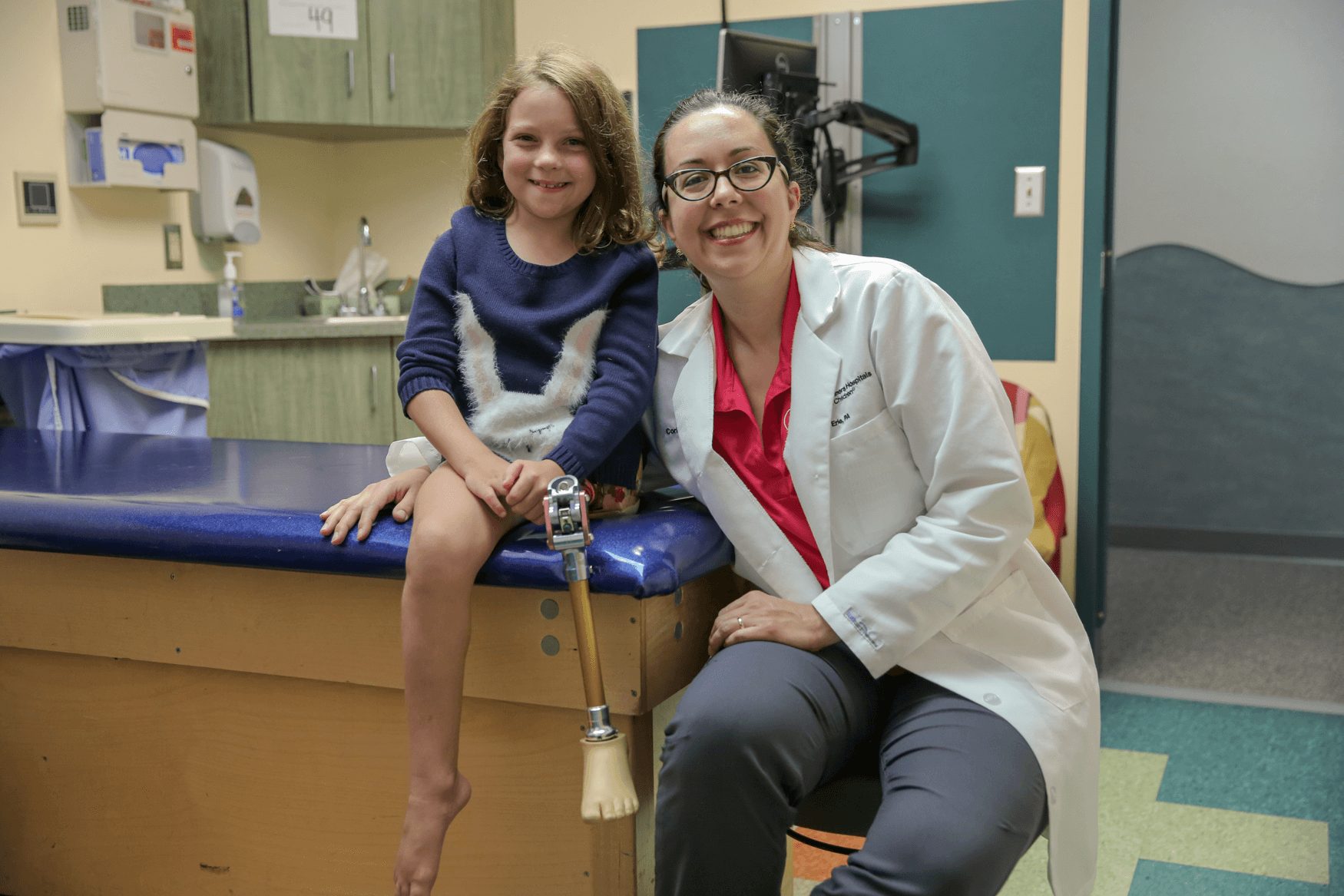 Girl Shriners patient with prosthetic leg smiles alongside female doctor
