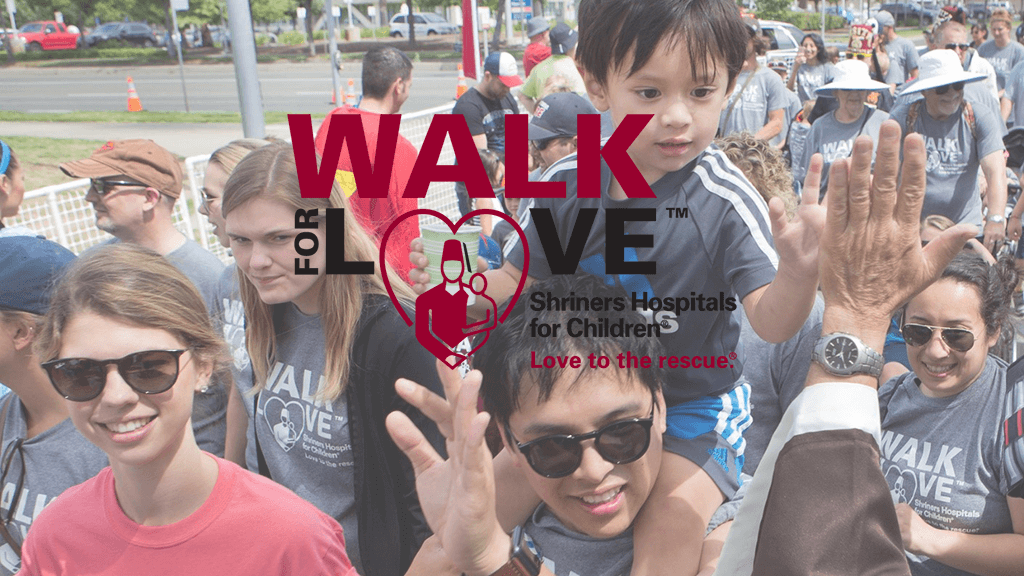 Young boy on fathers shoulders gives high five at walk for love event